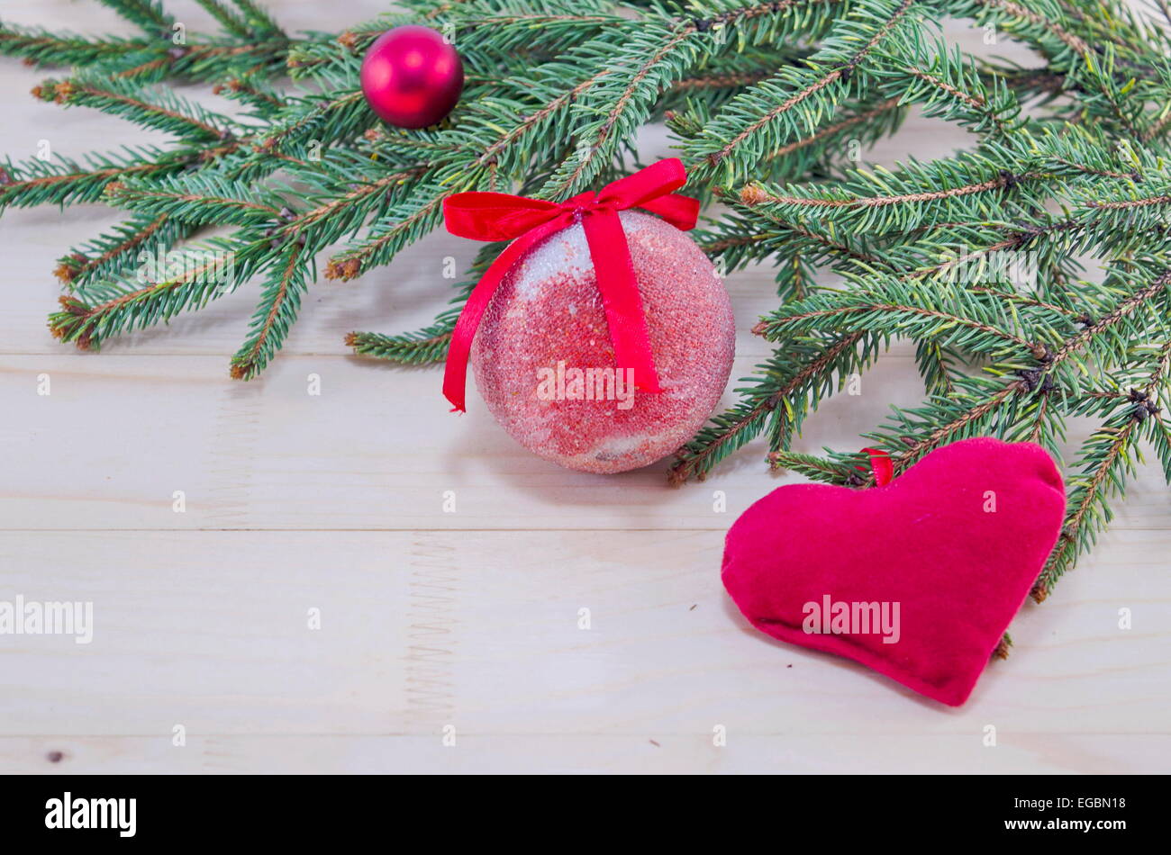 Rote Weihnachtskugeln und eine Tanne auf einem Holztisch Stockfoto