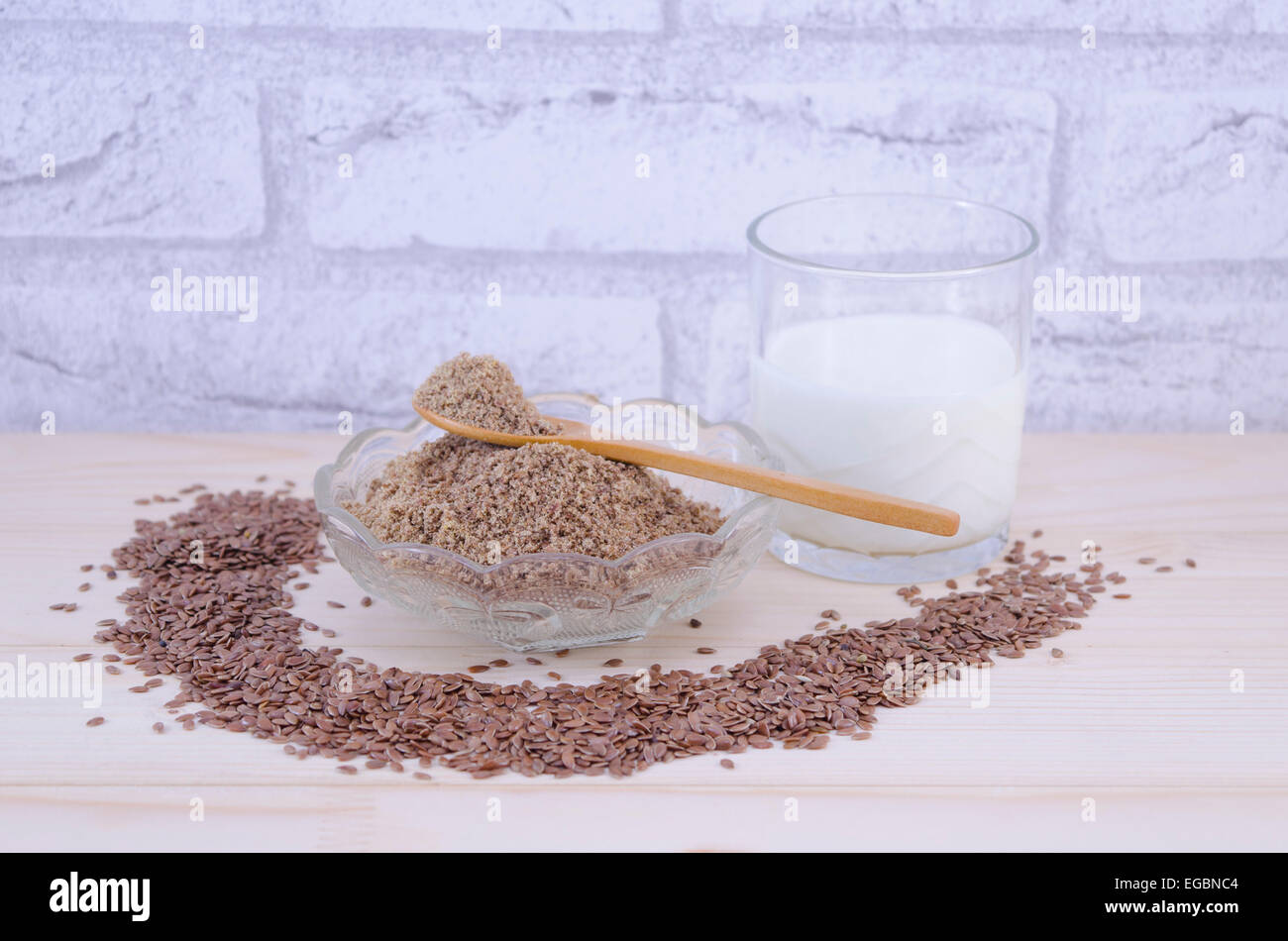 Glas Joghurt und Flachs Samen, ganze und gründet auf einem Holztisch Stockfoto