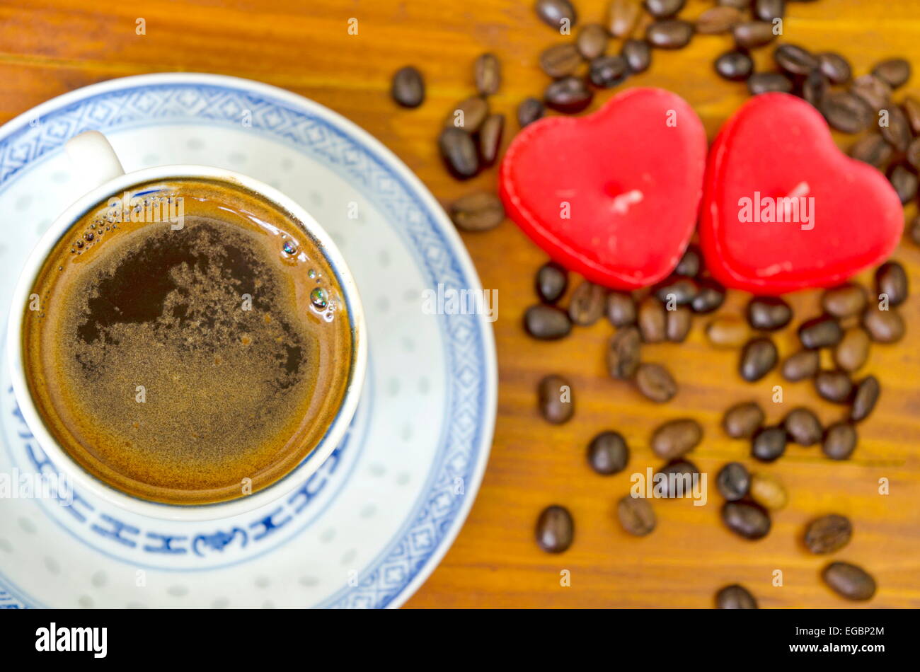 Tasse schwarzen Kaffee, Kaffeebohnen und romantische Herz geformt Kerzen auf einem Wodeen Tisch Stockfoto