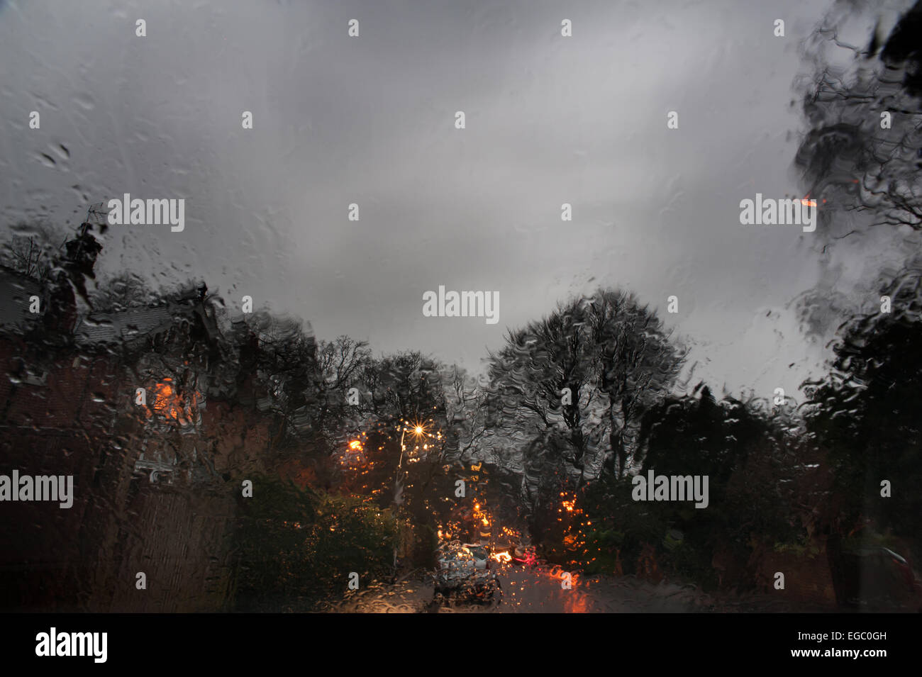 tristen nassen stumpf Abenddämmerung Blick durch die Windschutzscheibe des Autos als die Nacht hereinbricht und Haus Skyline wird mit Kunstlicht beleuchtet. Stockfoto