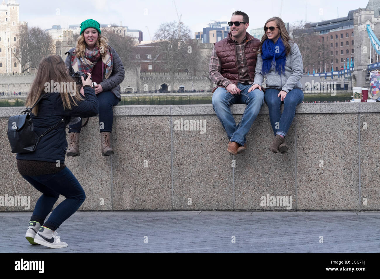 Es ist Urlaubszeit in London, Vereinigtes Königreich. Touristen sitzen an Wand an der Themse mit Handumdrehen Urlaub genommen Stockfoto