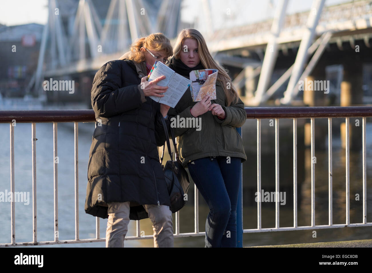 Zwei Frauen lesen einen Reiseführer zu London am Ufer der Themse Stockfoto