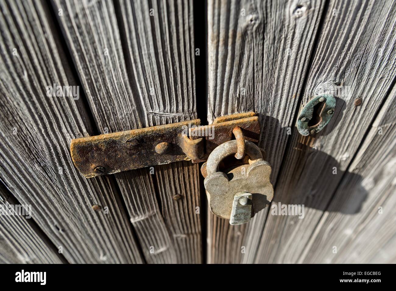 Alte und rostige Vorhängeschloss sichert einem alten, verwitterten hölzernen Tür. Stockfoto