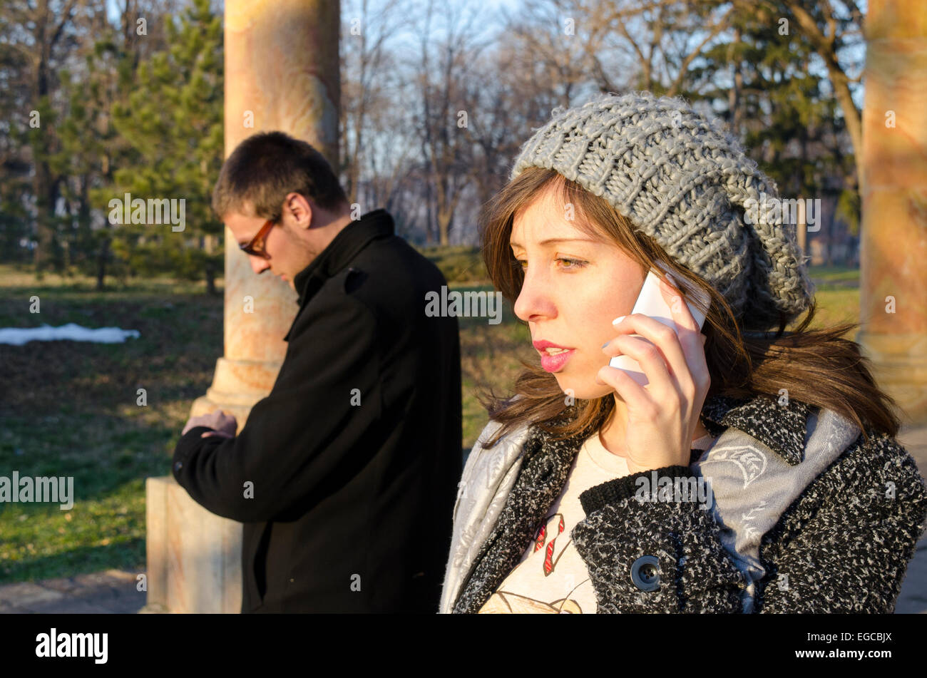 Mädchen am Telefon zu sprechen, während der junge in einem Park im freien wartet Stockfoto