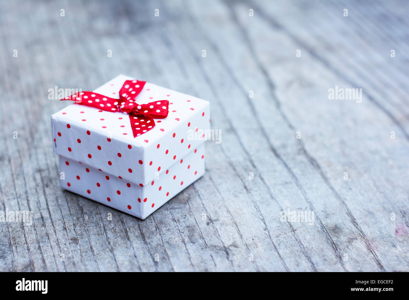 Weißen Geschenkbox mit roten Punkten auf hölzernen Hintergrund platziert Stockfoto