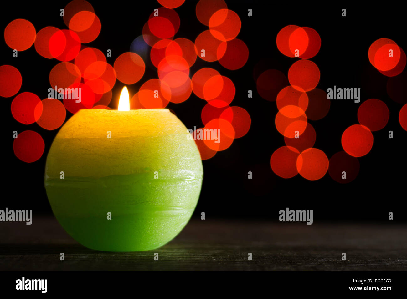 Kerzen leuchten platziert auf hölzernen Hintergrund mit roten Bokeh-Effekt Stockfoto