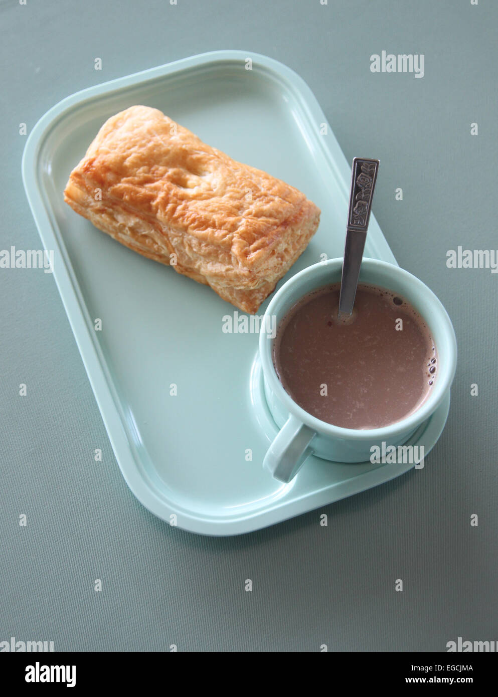 Patty und heißem Kakao in einem blauen Teller am Esstisch. Stockfoto
