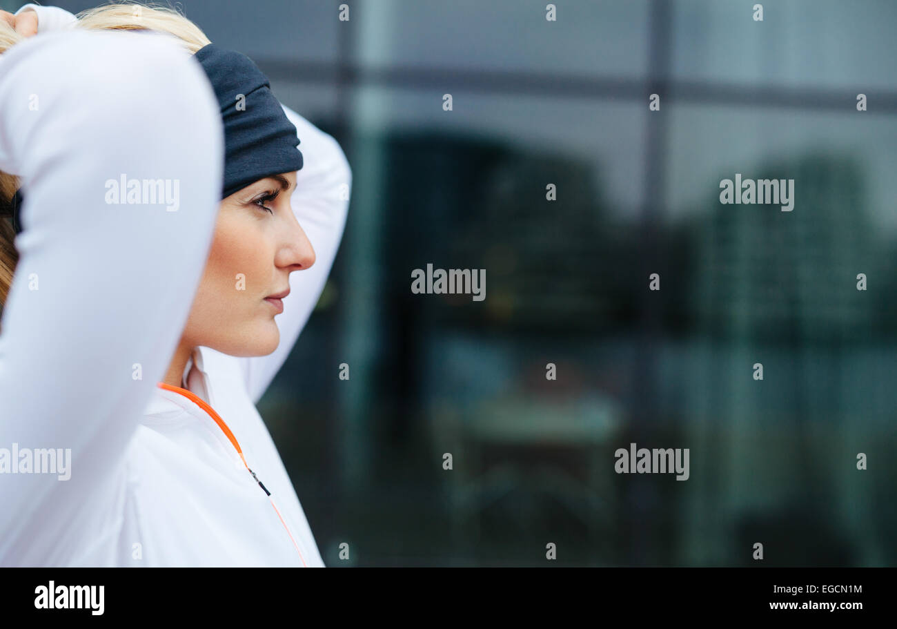 Seitenansicht des attraktiven weiblichen Athleten bereit für einen Lauf in der Stadt. Zuversichtlich und motiviert Fitness Frau wegsehen. Stockfoto