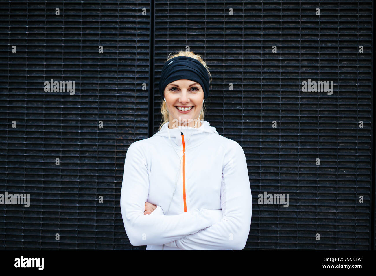 Porträt der glückliche junge Frau in Sportkleidung, Blick auf die Kamera zu Lächeln. Fitness Frauen gegen dunkle Wand. Stockfoto