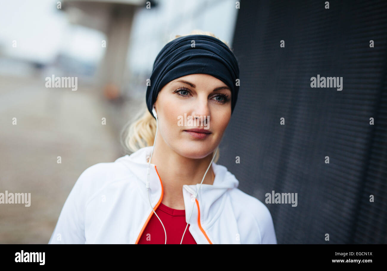 Close-up Portrait attraktive und sportliche Frau trägt Stirnband und Musik über Kopfhörer hören. Fitness-weiblich. Stockfoto