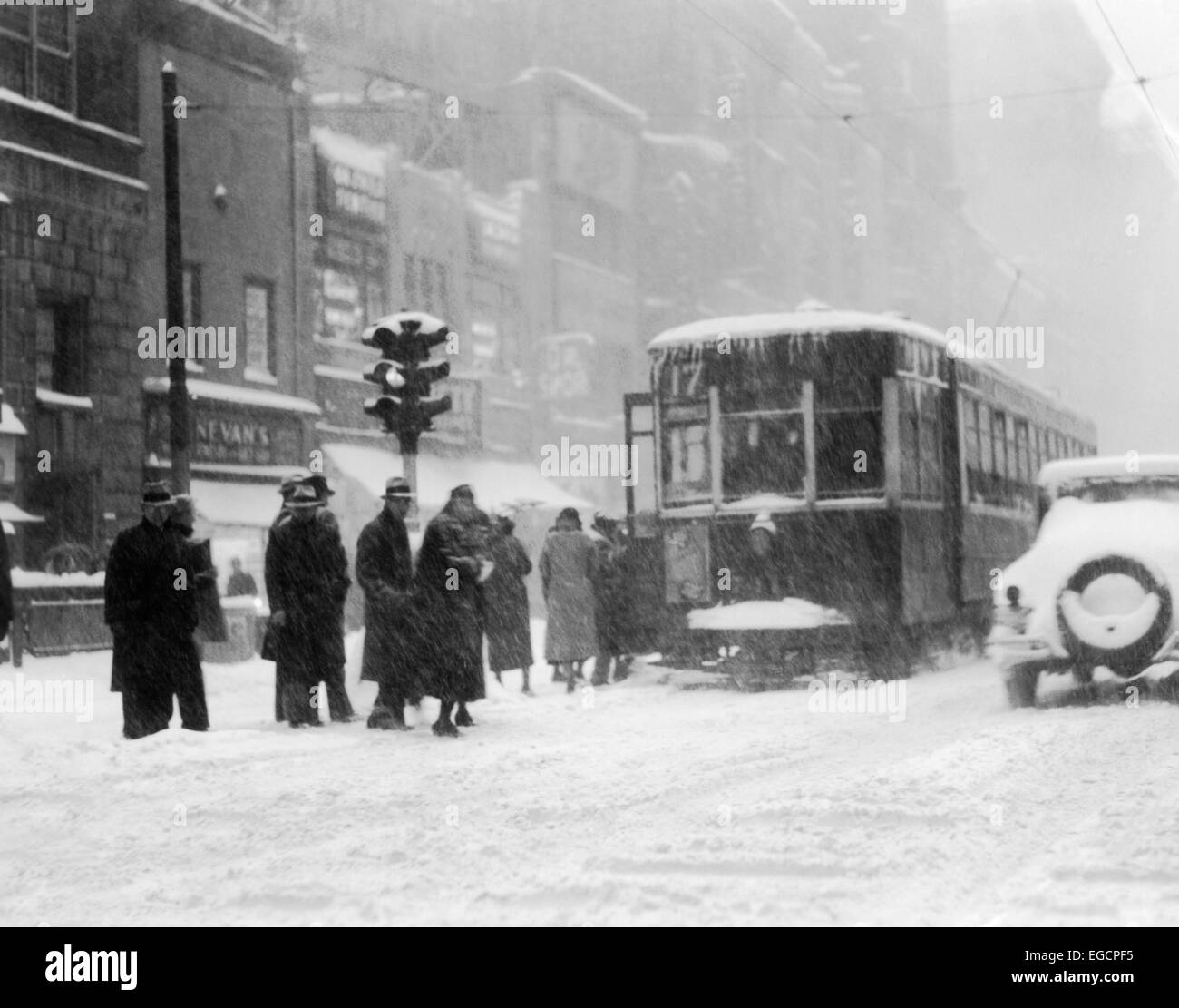 1930ER JAHREN FUßGÄNGER AUF SCHNEE BEDECKTEN EISIGEN WINTER STREET IN PHILADELPHIA AUF STRAßENBAHN DURCH AMPEL Stockfoto