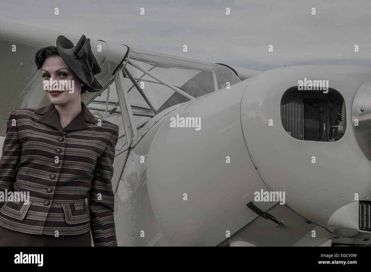 Ein Mädchen in Kostümen neben einem Flugzeug am Goodwood Revival 2014 posieren. Frauen in klassischen Vintage Zeitraum Kleid in der Luftfahrt Park Stockfoto