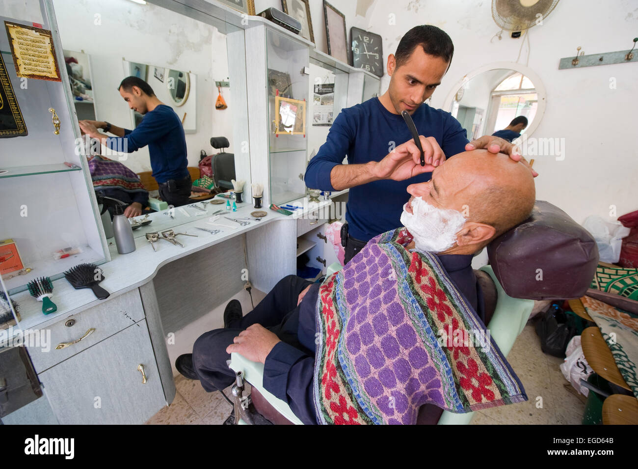 HEBRON, ISRAEL - 10. Oktober 2014: ein Barbier rasieren ist einen Mann in seinem kleinen Friseurladen in der Mitte der alten Stadt von Hebron Stockfoto