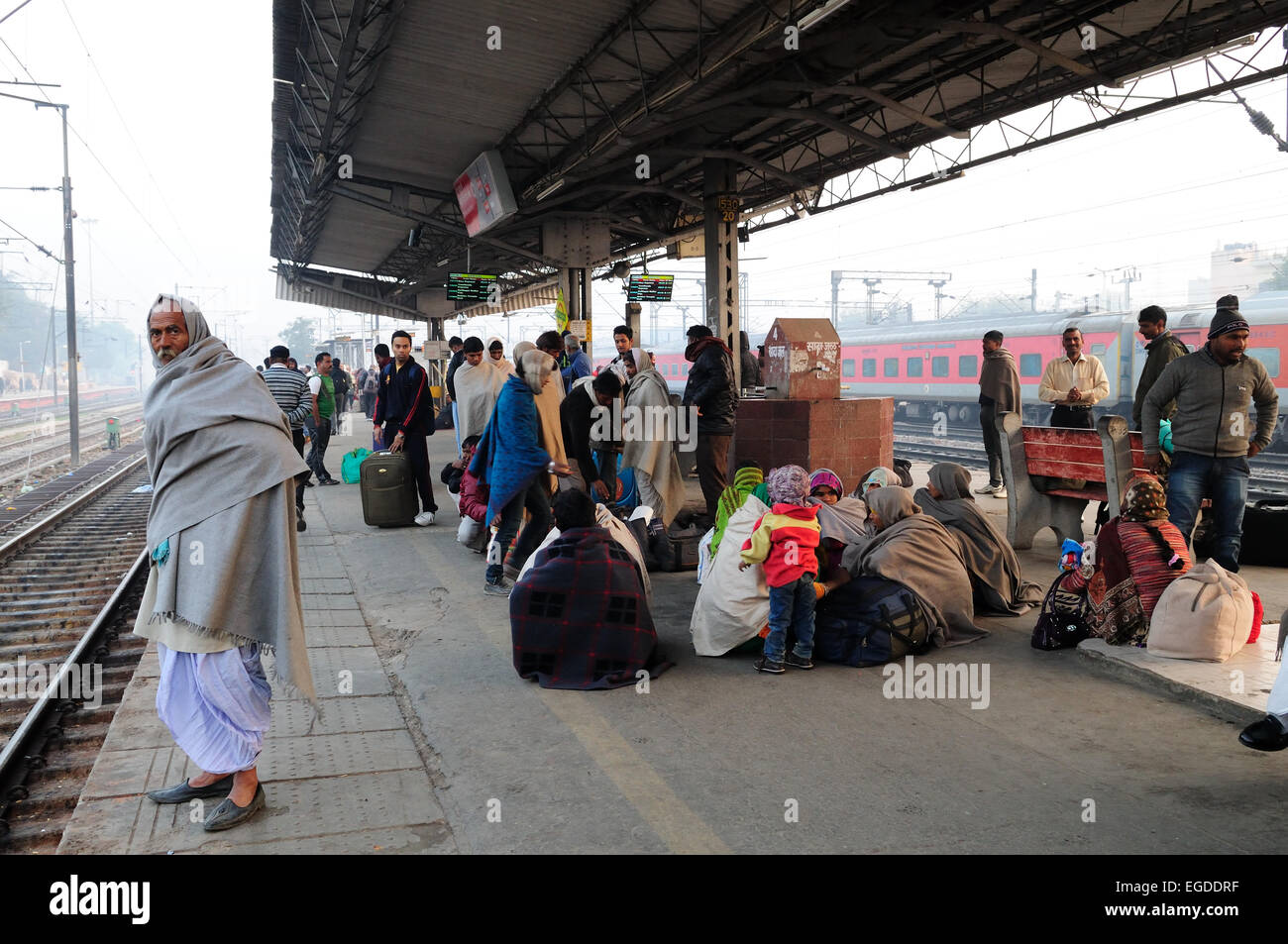 Menschen stehen und sitzen auf der Plattform von Delhi Railway Station warten am frühen Morgen trainieren Indien Stockfoto