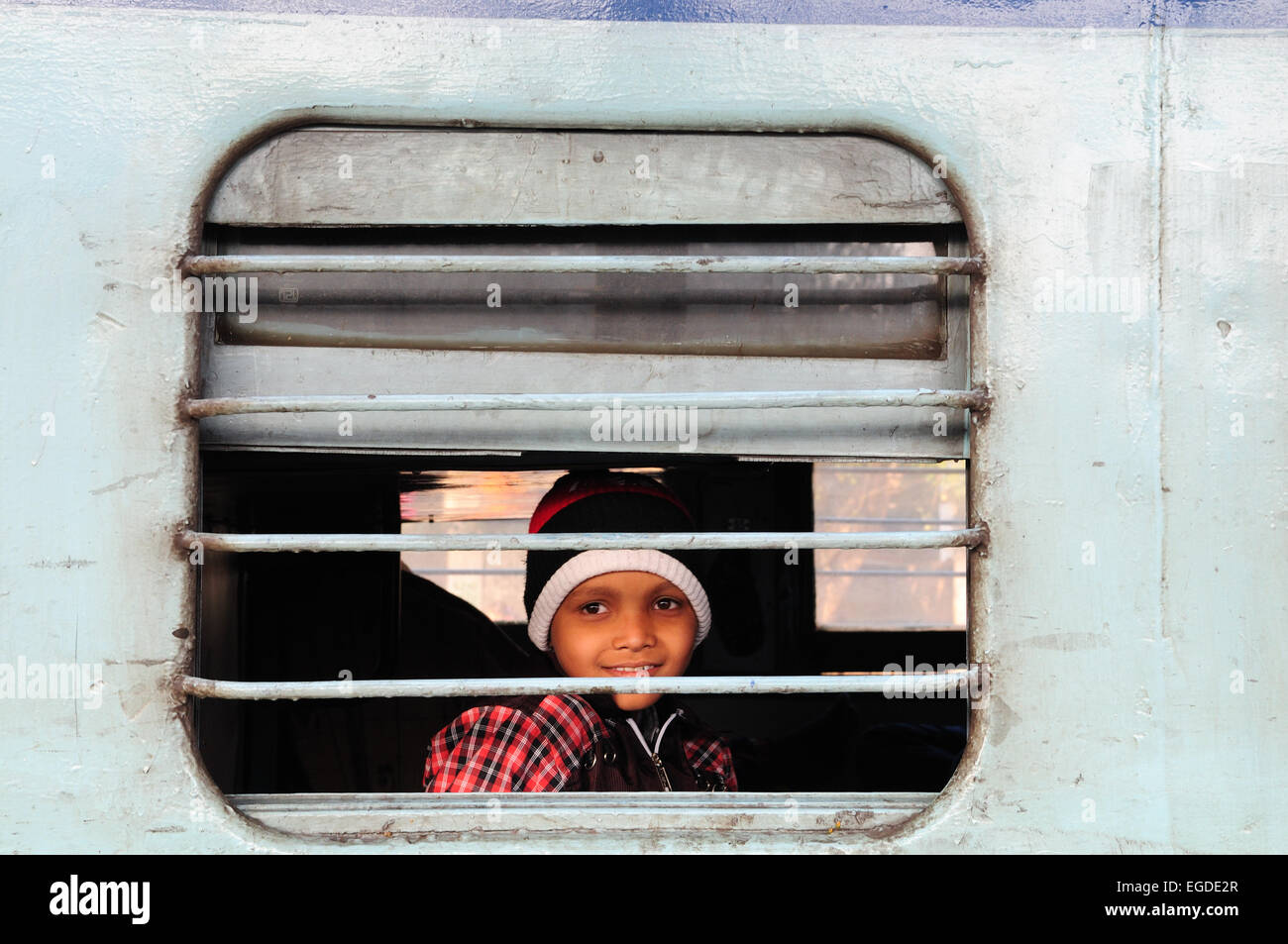 Lächelnden jungen durch die Gitterstäbe ein Zugfenster Indien Delhi Railway Station suchen Stockfoto