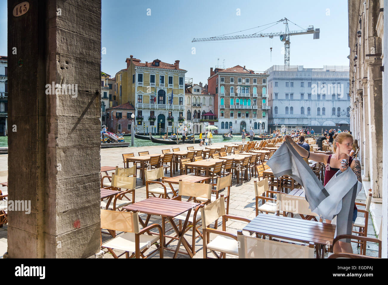 Venedig, Italien-August 12, 2014: eine junge Kellnerin aufräumt die Tabellen eines Balkens entlang des Kanals in Venedig an einem sonnigen Tag Stockfoto