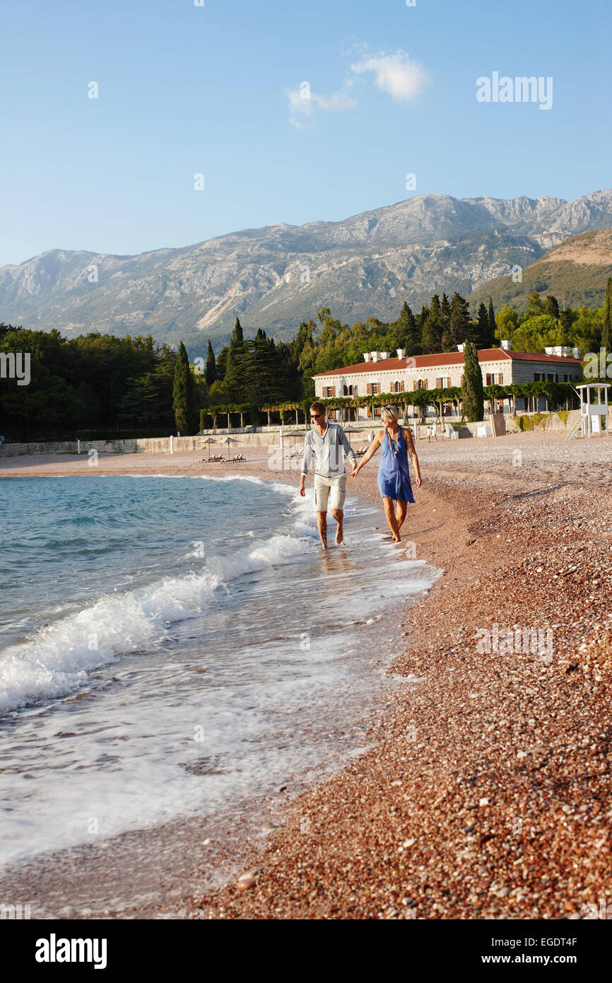 Paar am Strand, Villa Milocer im Hintergrund, Aman Sveti Stefan, Sveti Stefan, Budva, Montenegro Stockfoto