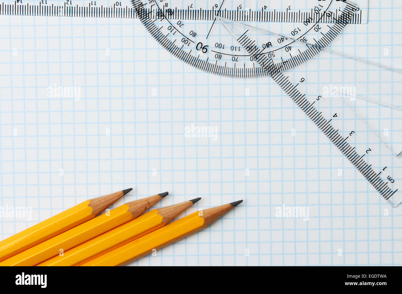 Bleistifte, Regel, Winkelmesser und Geodreieck auf Zeichenpapier mit Maßeinteilung Stockfoto