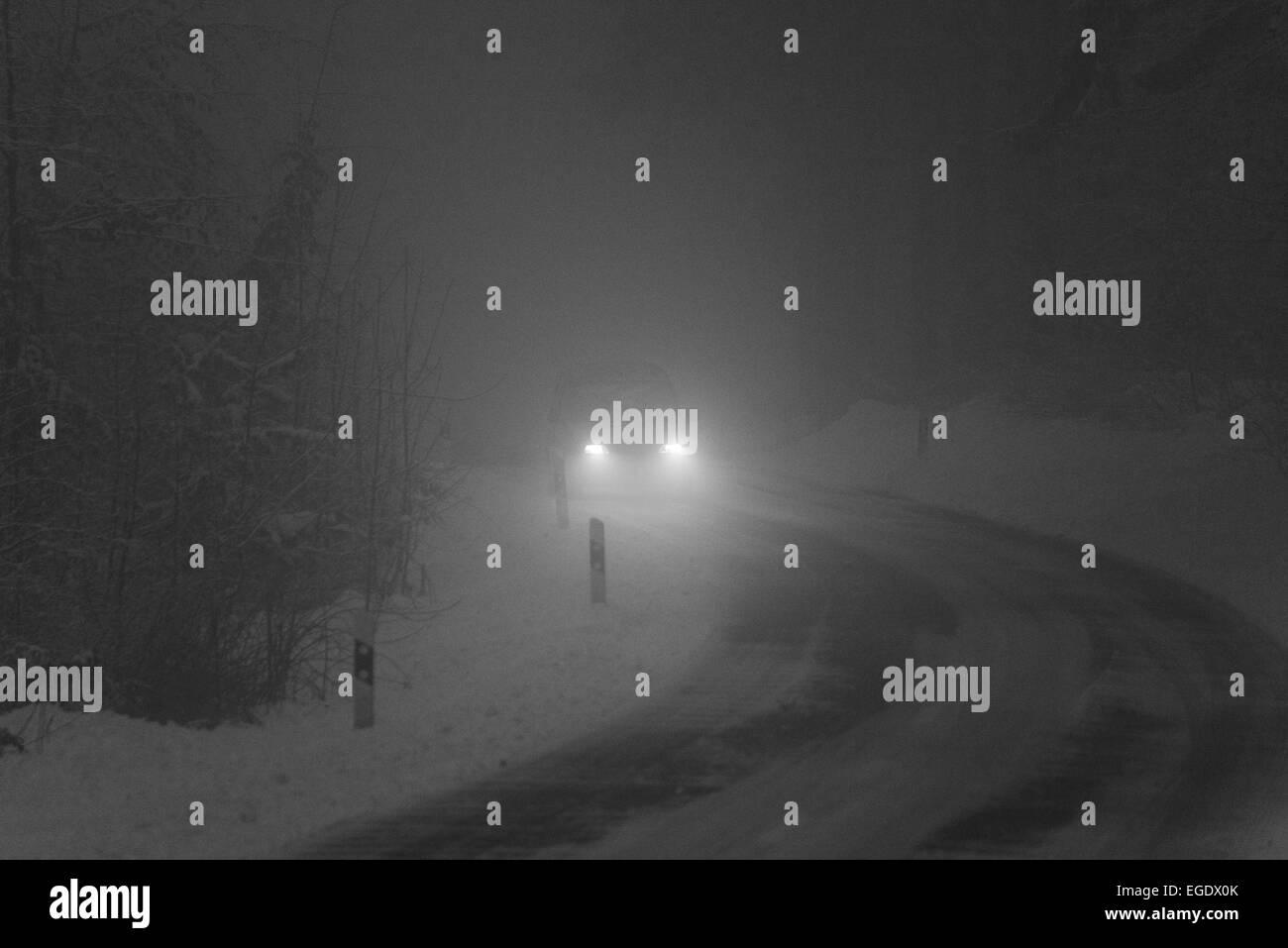 ein Auto durch die Dunkelheit in einer nebligen & verschneiten Umgebung Stockfoto