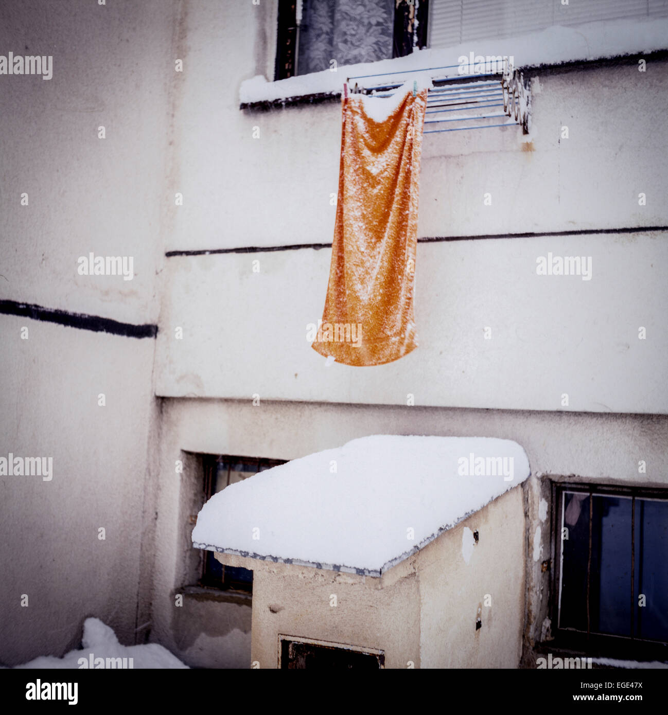 Orangefarbenes Handtuch, das vom Fensterschnee hängt Stockfoto