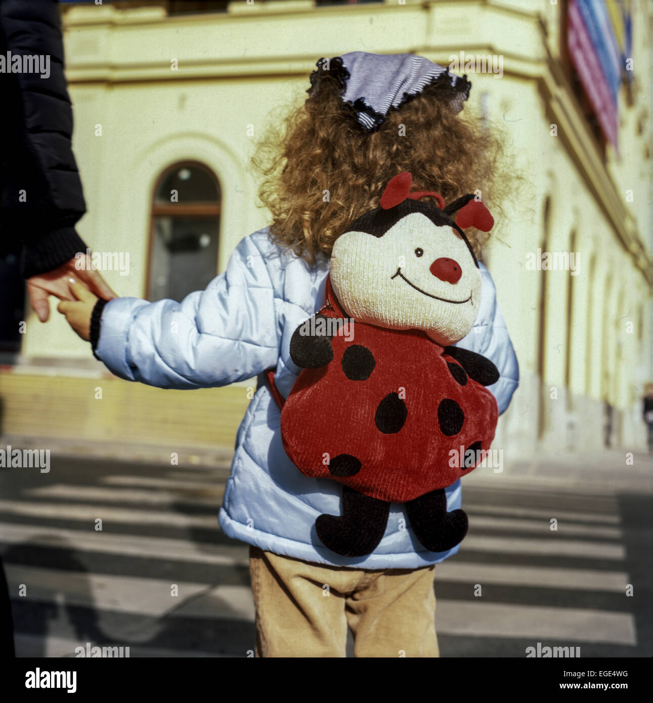 Kind auf dem Zebrastreifen Hände halten, Marienkäfer Tasche Stockfoto
