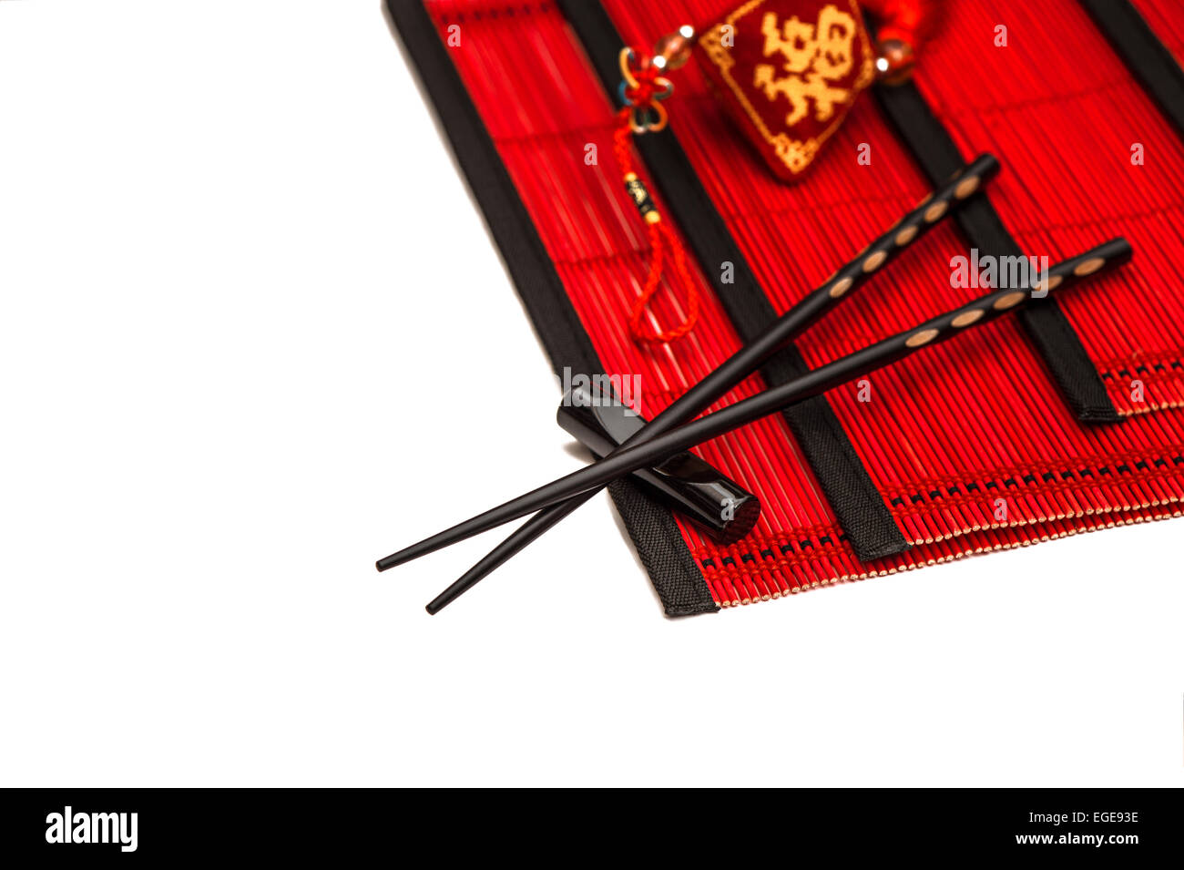Schwarzen Stäbchen auf roten Bambusmatte. Asiatischen Stil Tabelle Gedeck mit chinesischen Neujahr Ornament. Glücksbringer Stockfoto