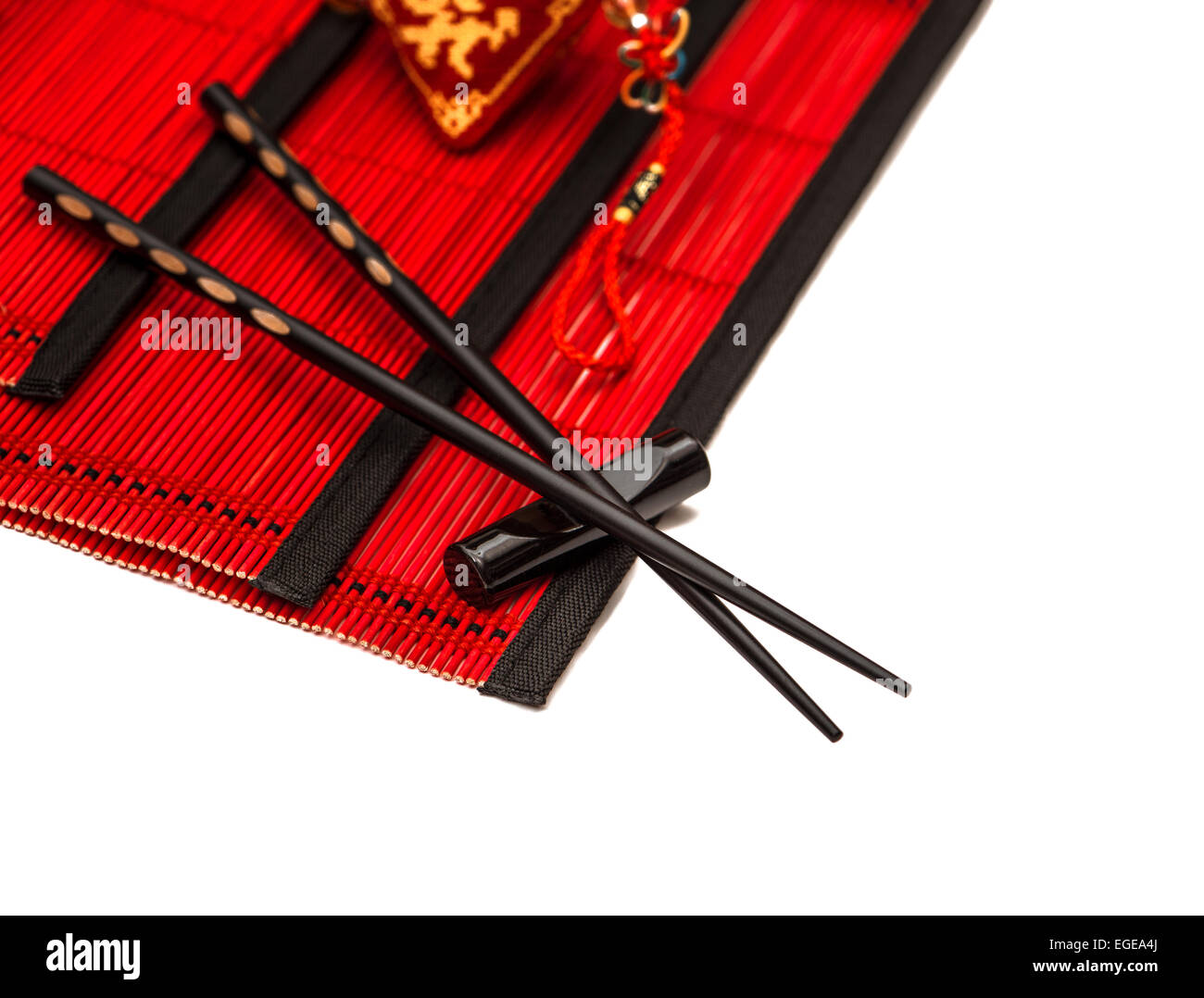 Schwarzen Stäbchen auf roten Bambusmatte. Asiatischen Stil Tabelle Gedeck mit chinesischen Neujahr Glücksbringer Stockfoto