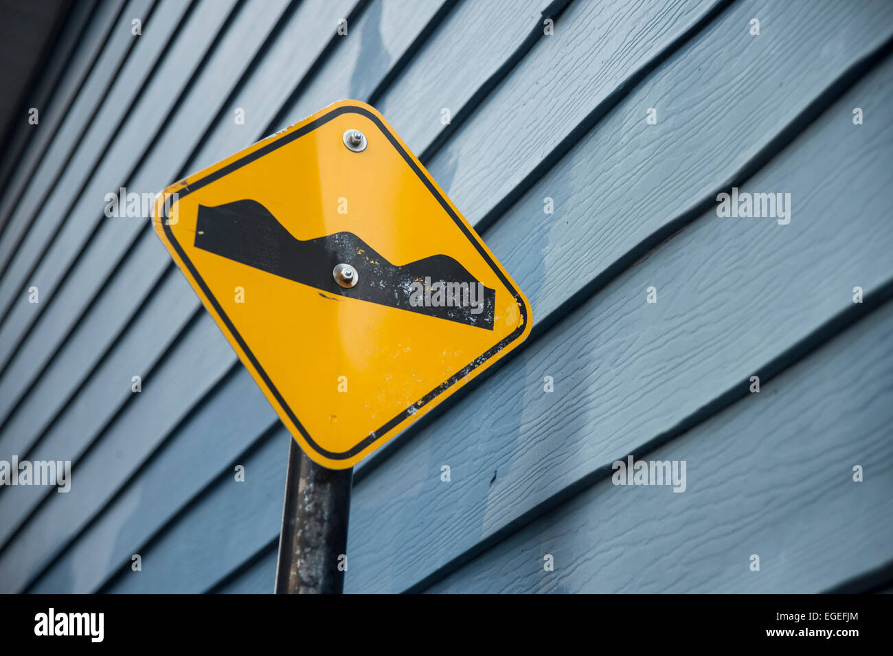 Beule / rauhe Straße Fahrbahn Zeichen vor einer blauen Wand aus Holz Stockfoto