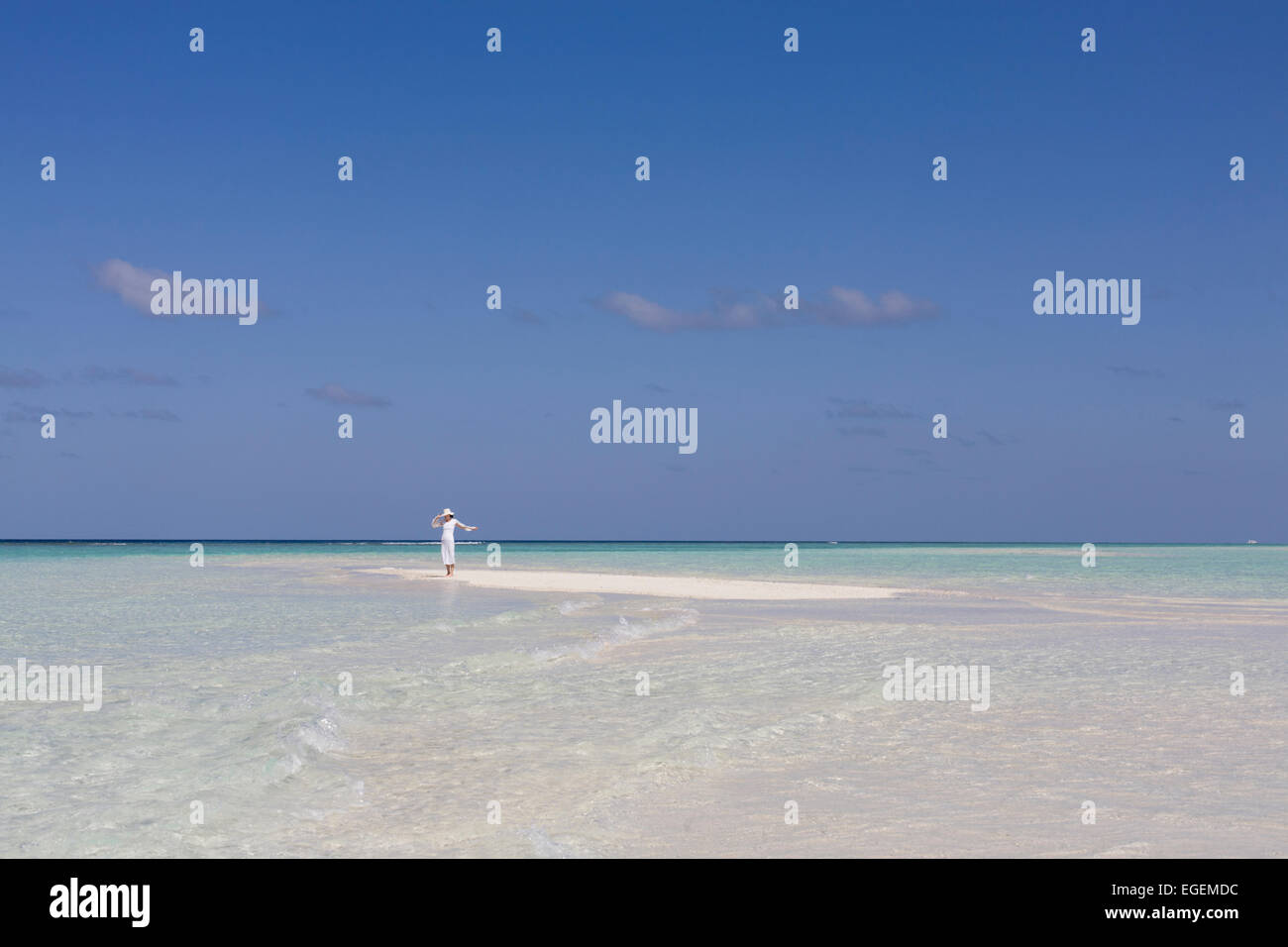 Junge Frau an einsamen weißen Sandstrand, umgeben von tropischen Gewässern auf den Malediven in der Nähe von Indien genießen Sonnenlicht Stockfoto