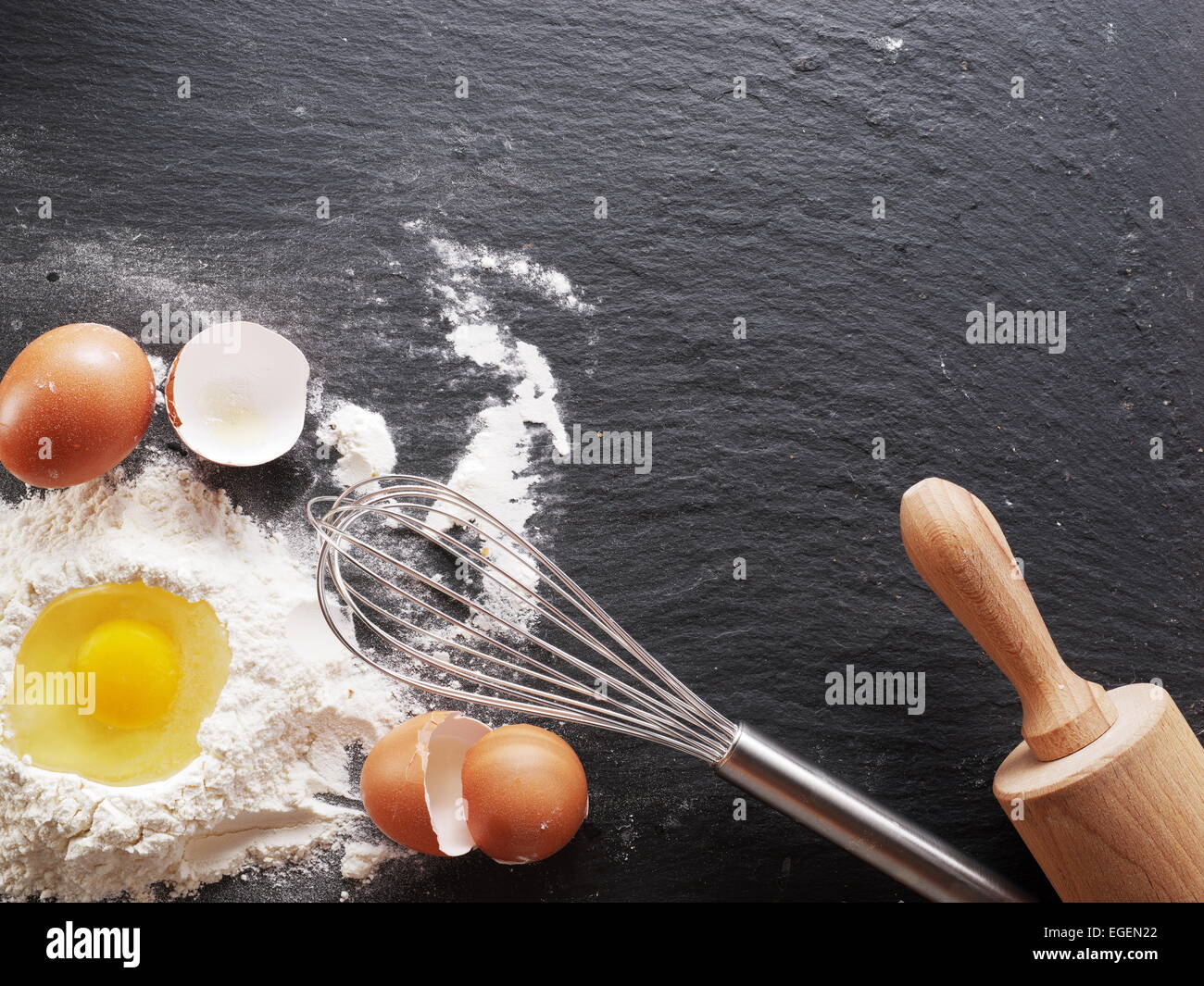Teigbereitung. Backzutaten: Ei und Mehl am schwarzen Brett. Stockfoto