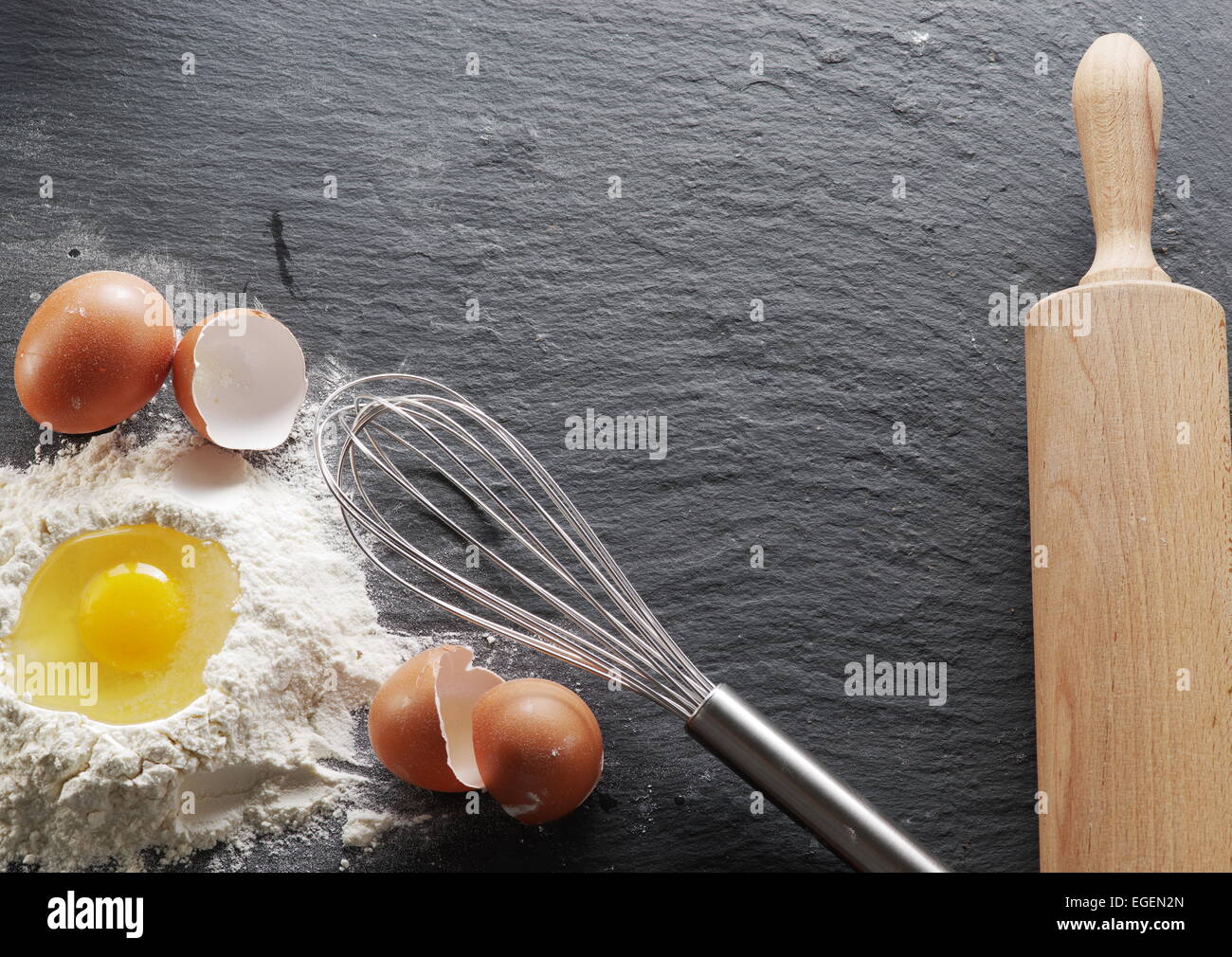 Teigbereitung. Backzutaten: Ei und Mehl am schwarzen Brett. Stockfoto