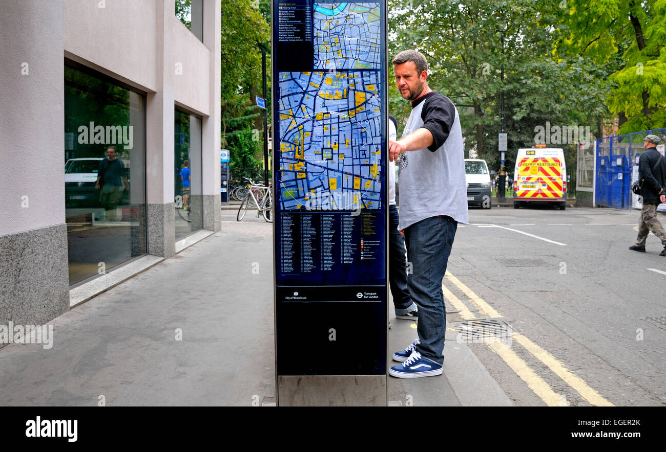 London, England, Vereinigtes Königreich. Mann sucht sich eine Touristenkarte in Soho Square Stockfoto