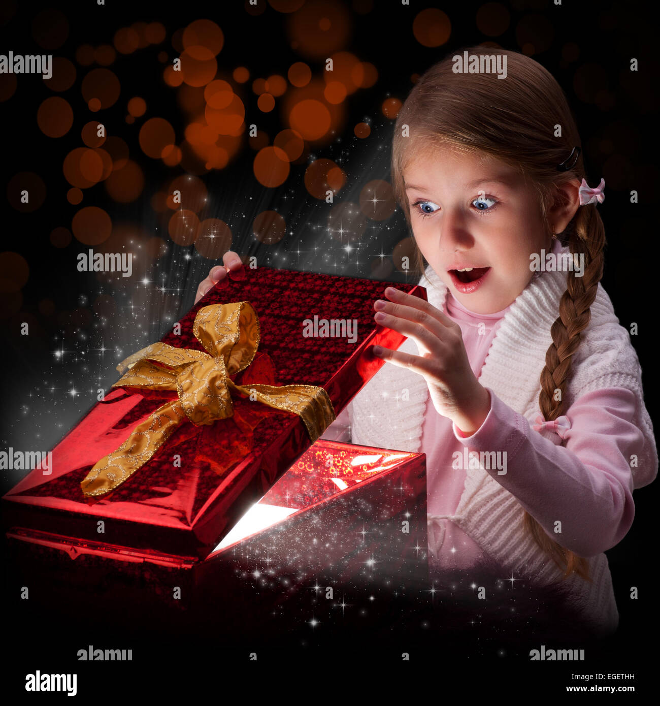 Das Mädchen mit abstrakten Licht aus einer Geschenkbox geliefert. Emotion eine Überraschung. Ein dunkler Hintergrund Stockfoto