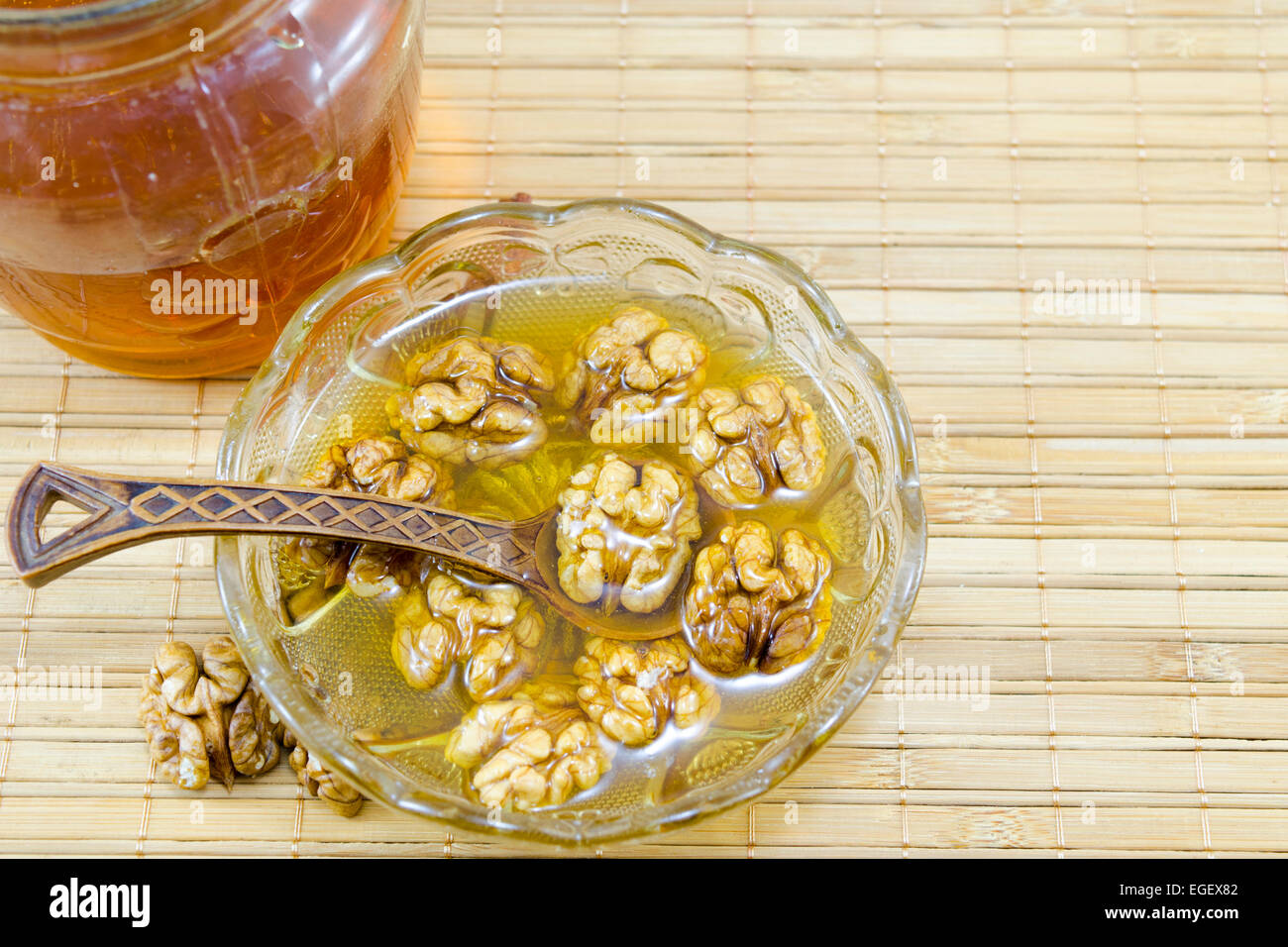 Walnüssen und Honig in einem Glas auf einem Bambus-Tisch Stockfoto