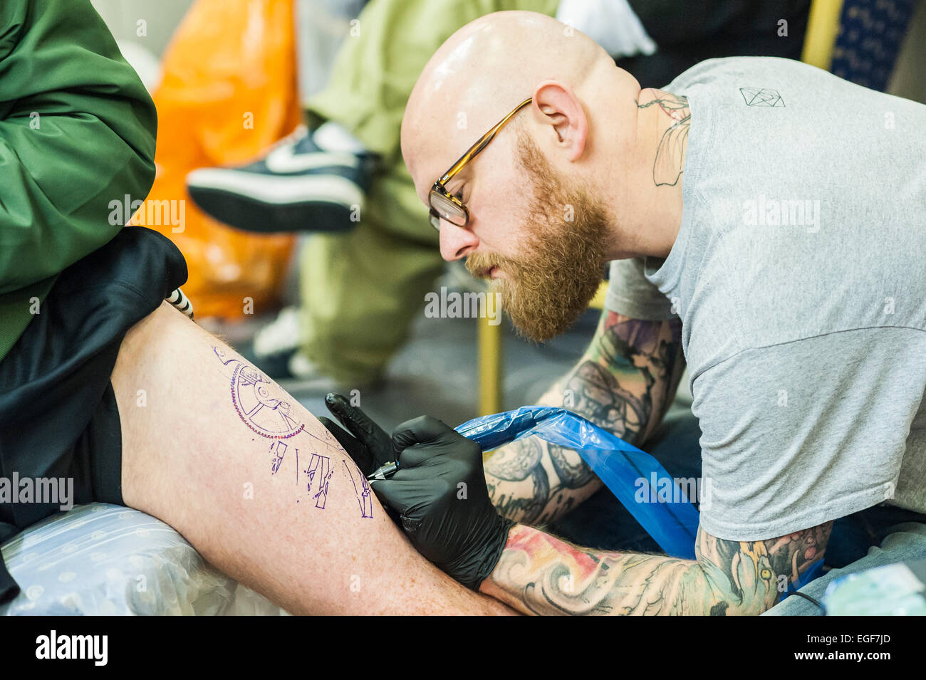 Ein Mann tätowiert am Bein auf der Brighton Tattoo Convention. Stockfoto