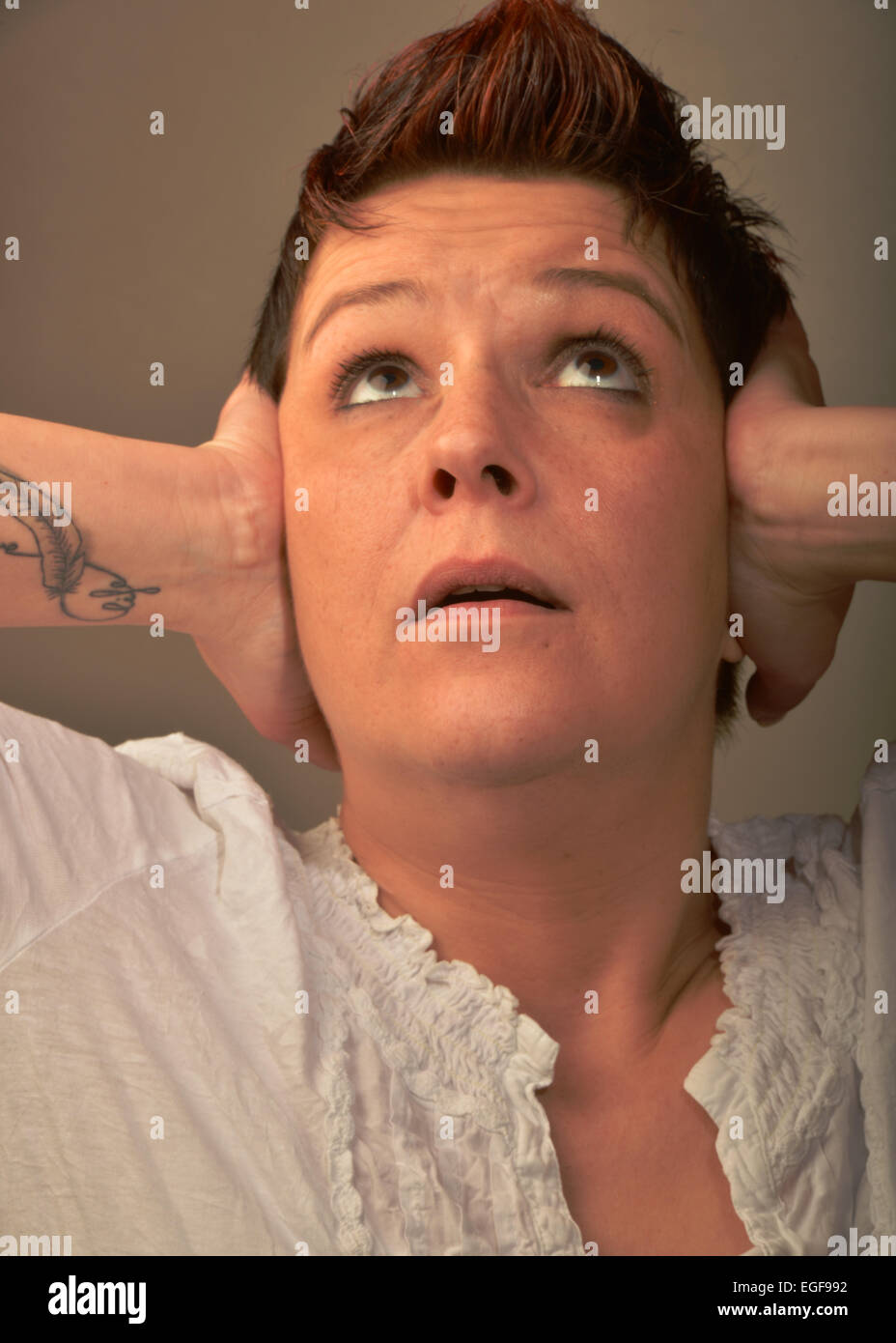 Eine junge Frau mit einem notleidenden Gesicht hält ihre Ohren. Foto auf 11.03.2014 in Iserlohn. Stockfoto