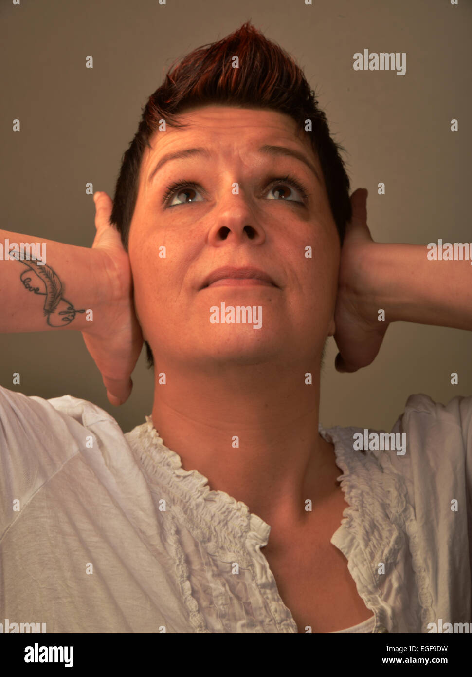 Eine junge Frau mit einem notleidenden Gesicht hält ihre Ohren. Foto auf 11.03.2014 in Iserlohn. Stockfoto