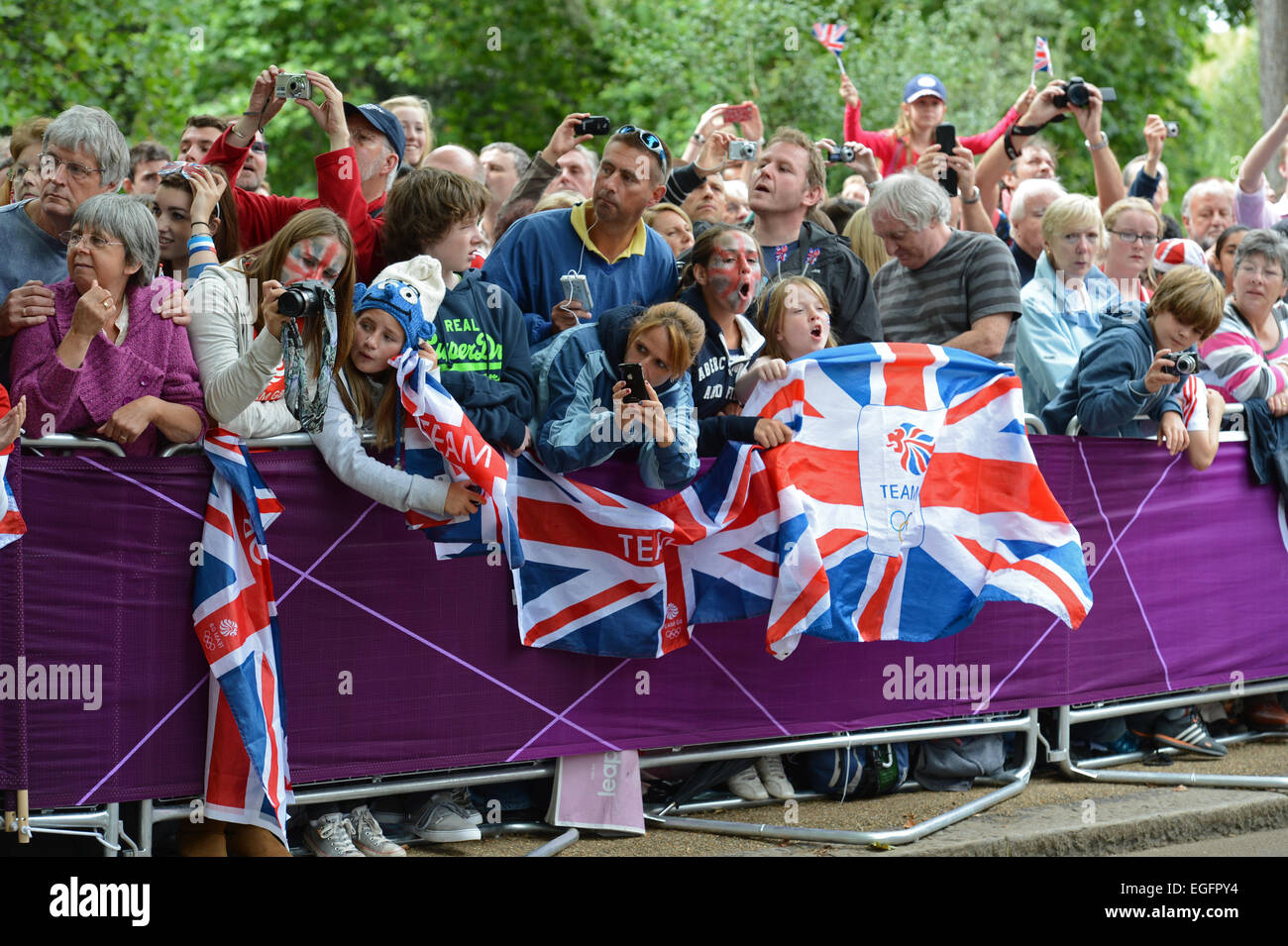 Sommer Radfahrer Radrennen auf einer Straße in England in einer Gruppe mit Zuschauer wehende Fahnen Stockfoto
