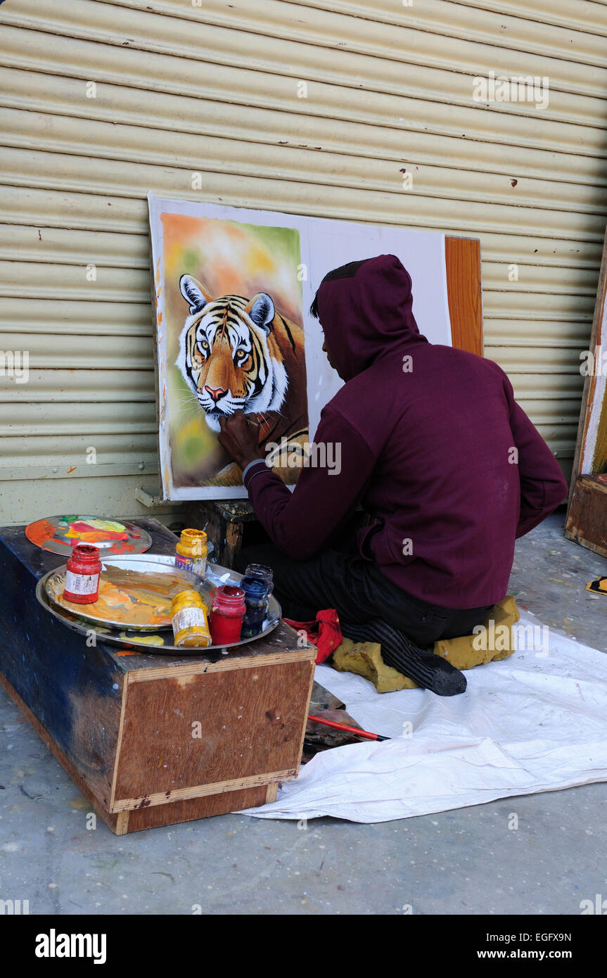 Indischer Mann sitzen auf dem Boden malen das Gesicht eines Tigers Madhya Pradesh, Indien Stockfoto