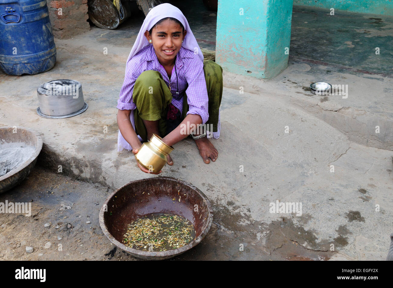 Lächelnden Inderin Reinigung ein Kupfer Kochtopf in ihre Stammes-Dorf Madhya Pradesh, Indien Stockfoto
