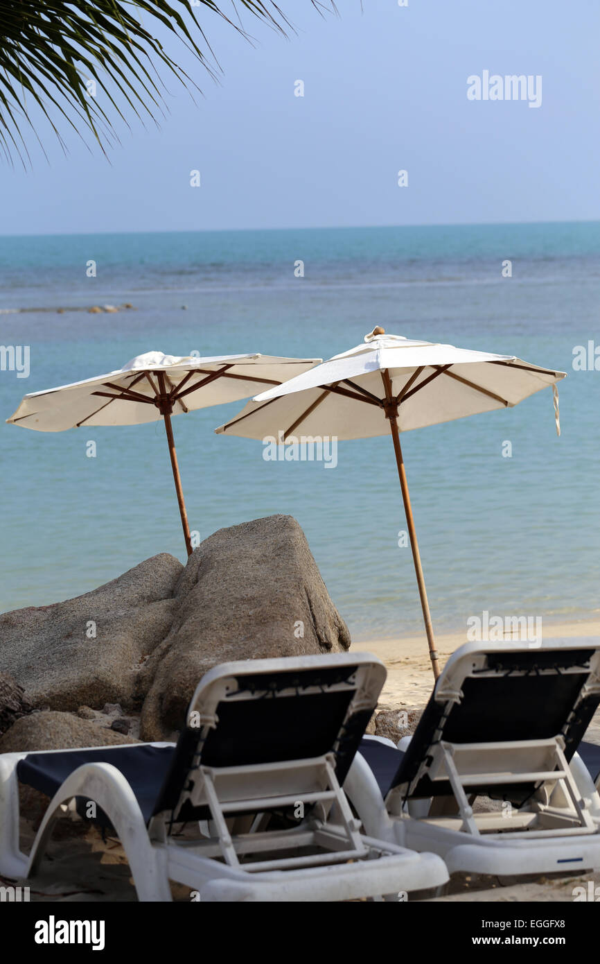 Sonnenliegen und Sonnenschirme zum Sonnenbaden am Strand in der Nähe von Meer Stockfoto