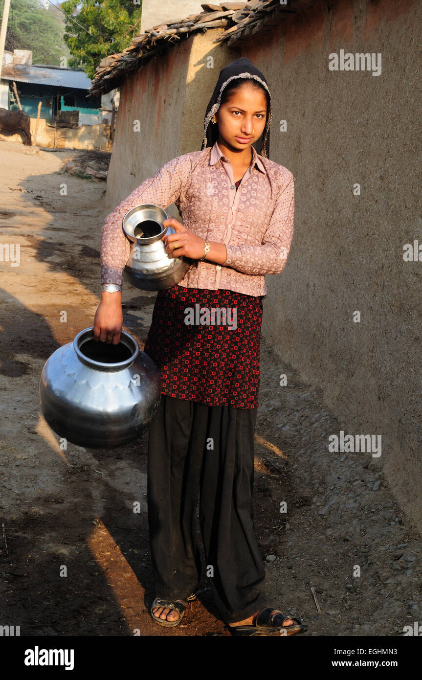 Ein indisches Mädchen halten Metall Töpfe, Wasser in ihre Tribal Dorf Madhya Pradesh, Indien zu sammeln Stockfoto