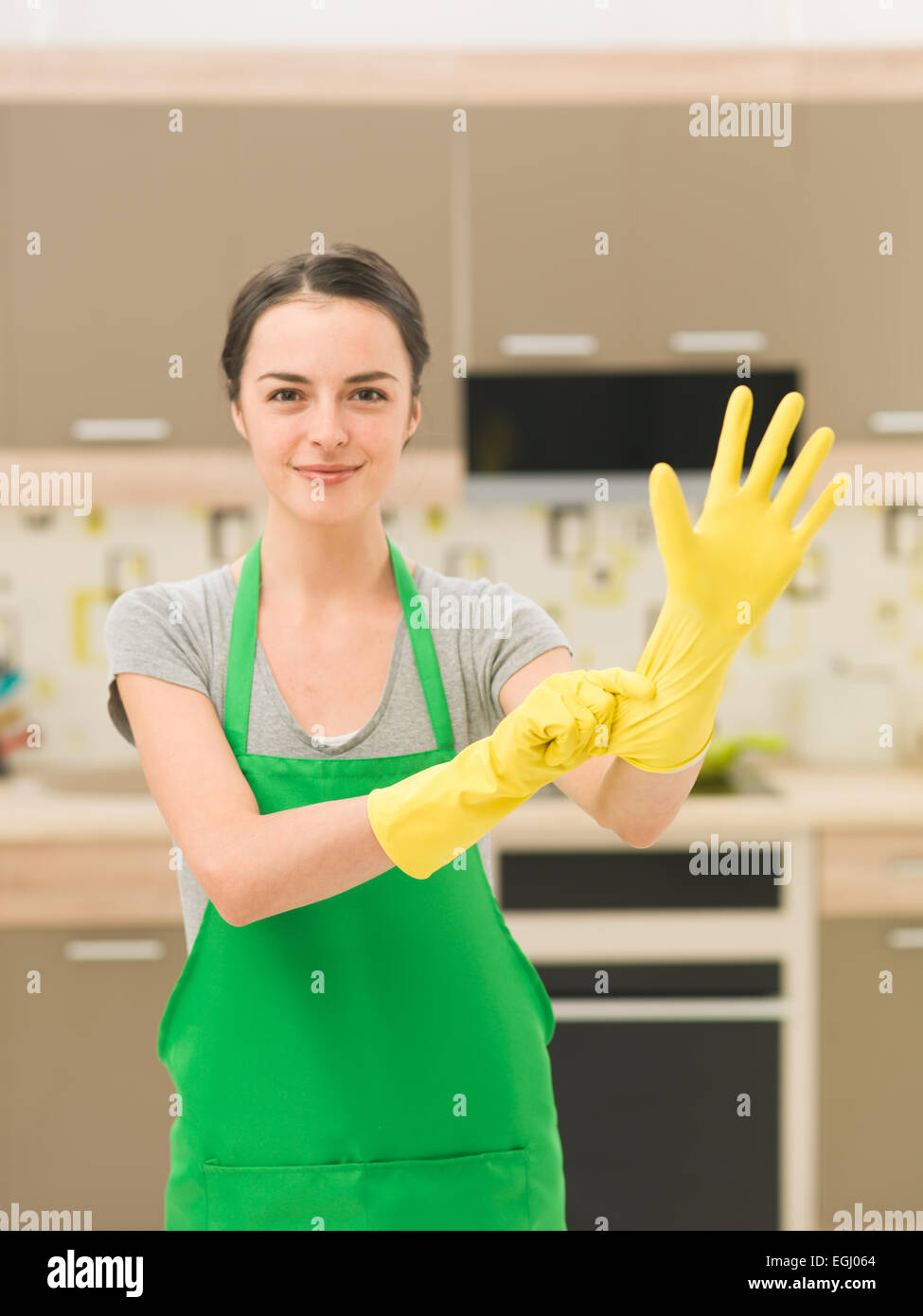 Glückliche Hausfrau Gummihandschuhe mit Küche zu Hause Hintergrund  aufsetzen Stockfotografie - Alamy