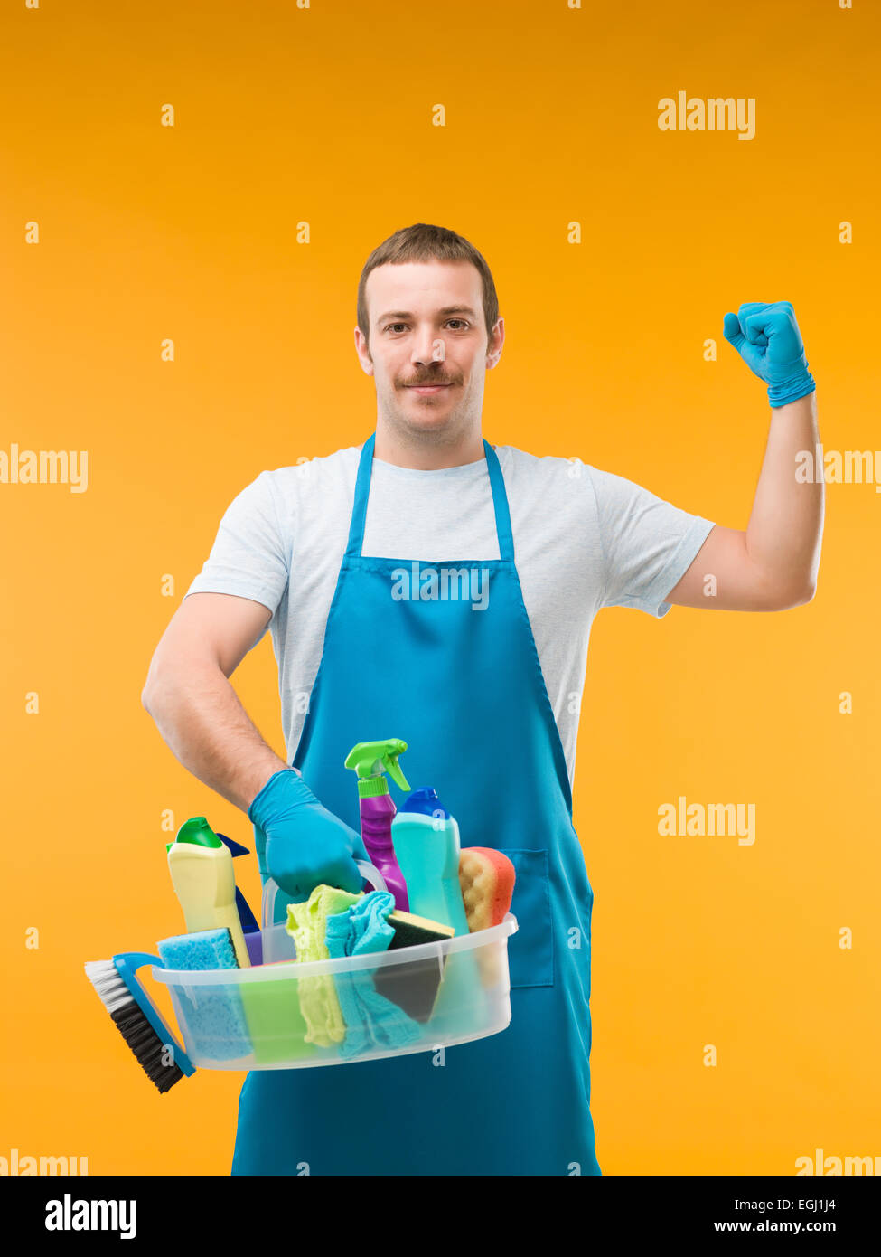 glücklich Hausmeister halten Reinigungsmittel und zeigt seine Armmuskeln Stockfoto