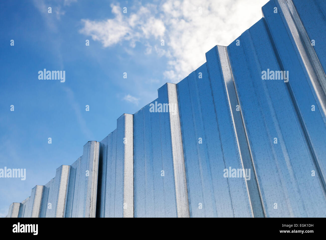 Glänzende corrugated Metallzaun und blauen Wolkenhimmel Stockfoto