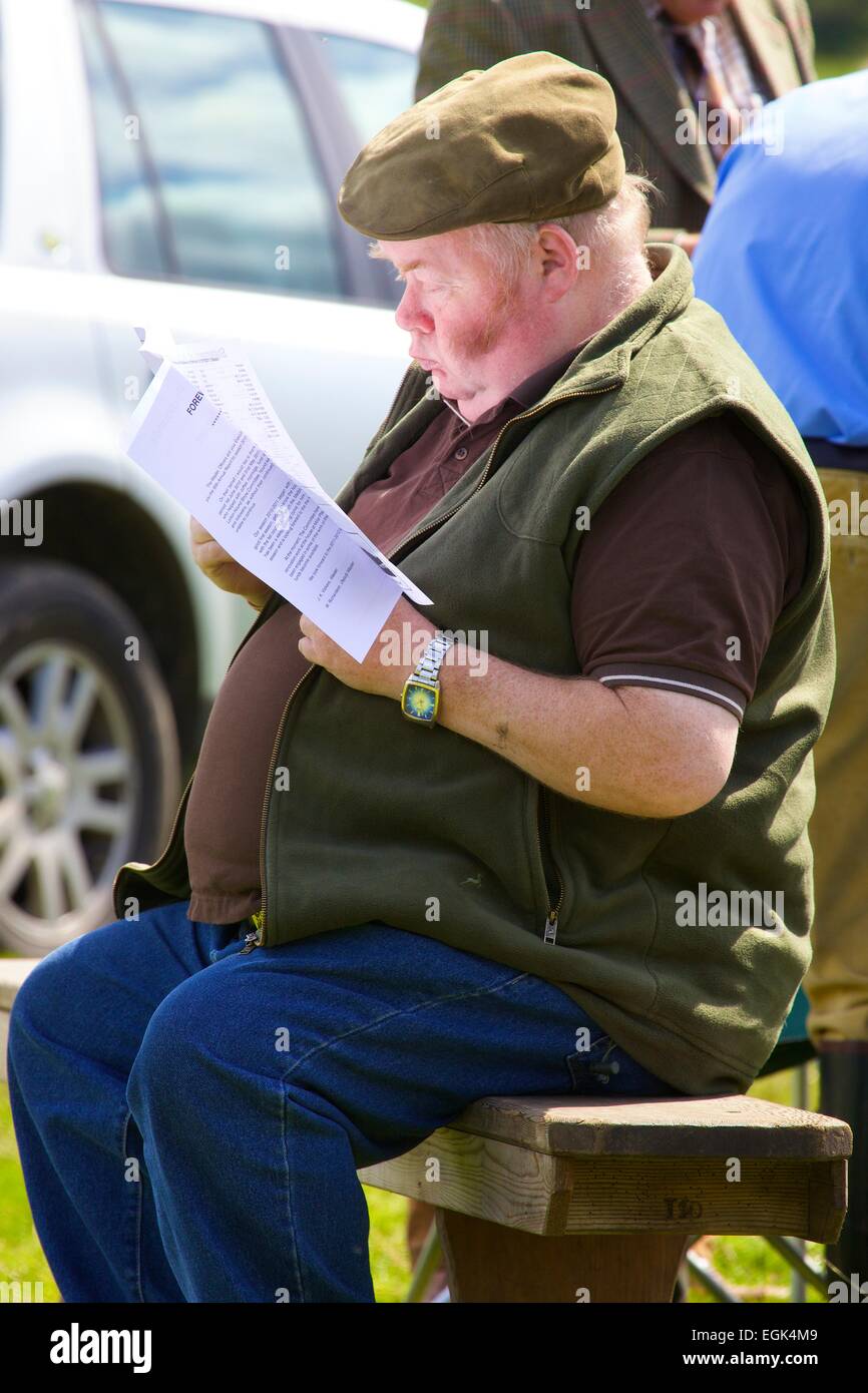 Großer Bauer lesen Broschüre auf der Bank sitzen. Threlkeld Show Threlkeld Keswick Seenplatte Cumbria England UK Stockfoto