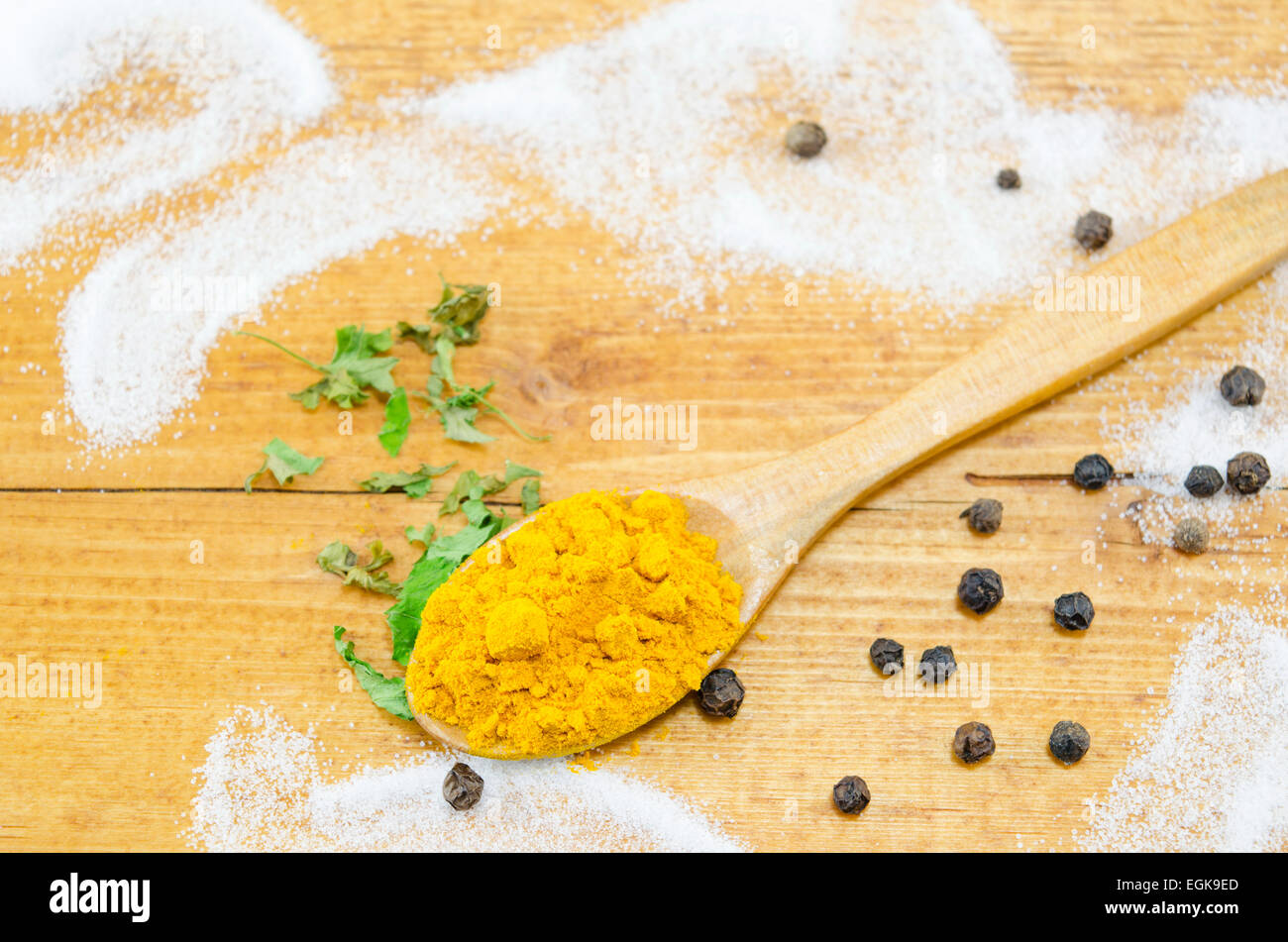 Curry in einem Holzlöffel auf einem Tisch dekoriert mit schwarzen Pepercorns, Salz und Petersilie Stockfoto