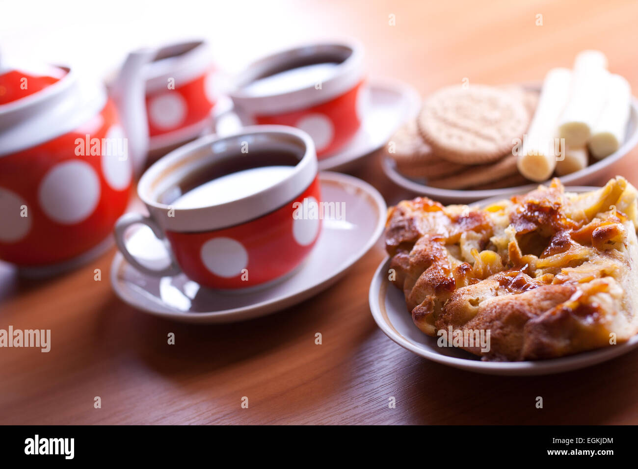 zwei Stück Apfelkuchen auf eine Front und drei Tassen Tee auf Hintergrund Stockfoto