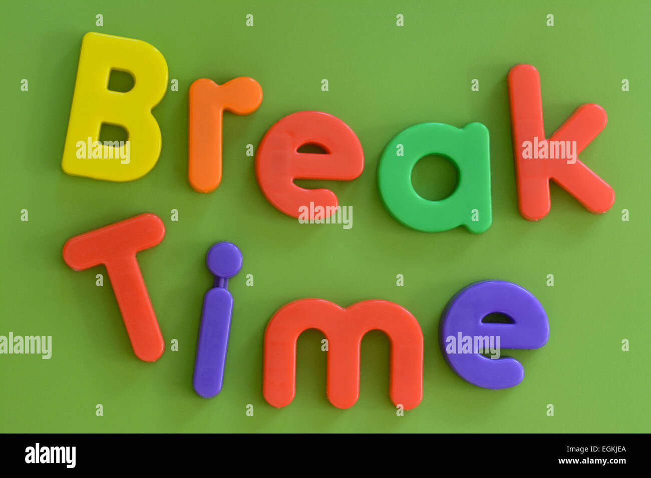 Nahaufnahme der Wörter zu brechen Zeit in bunten Kunststoff-Brief-Spielzeug auf grünem Hintergrund Stockfoto