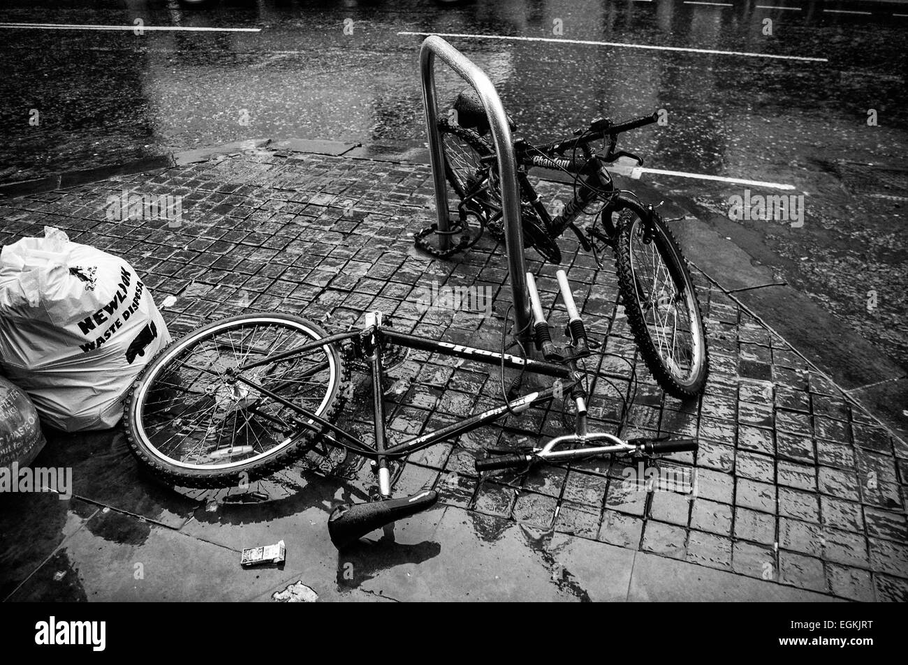 Schwarz-weiß Bild von zwei Fahrräder gesichert zu einem Fahrradständer, eine vandalized liegen in Manchester Street 2015 Stockfoto
